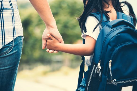 Cute girl with backpack holding her mother hand